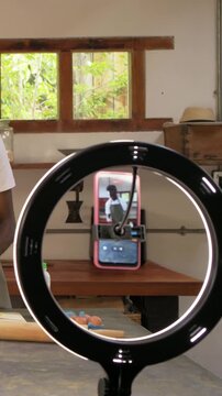 Vertical video: Whisking man in apron mixing batter in kitchen with ring light filming, copy space