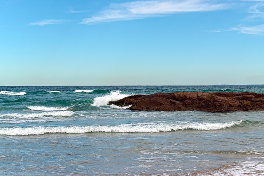 Waves Breaking Against Coastal Rock in Clear Blue Light