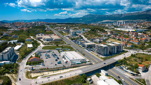 Aerial view of the urban landscape with a main highway, commercial buildings, and residential areas under a blue sky in Split, Split-Dalmatia County, Croatia.