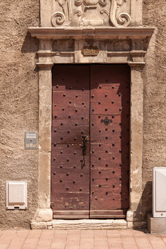 Weathered red door with metal studs and ornate stone frame