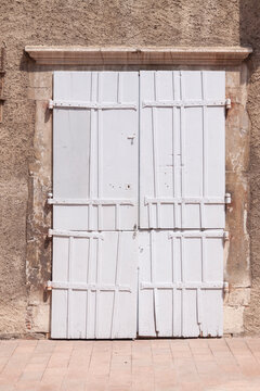 Weathered white doors stand against a rough stone wall