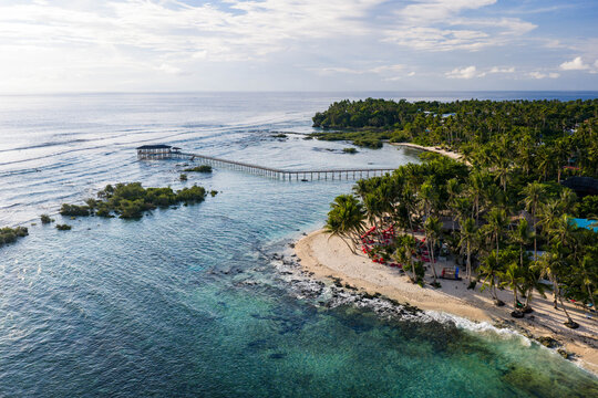 Aerial view of the Cloud 9 Surfing Area featuring the iconic wooden boardwalk extending over turquoise waters toward breaking waves in General Luna, Caraga, Philippines.