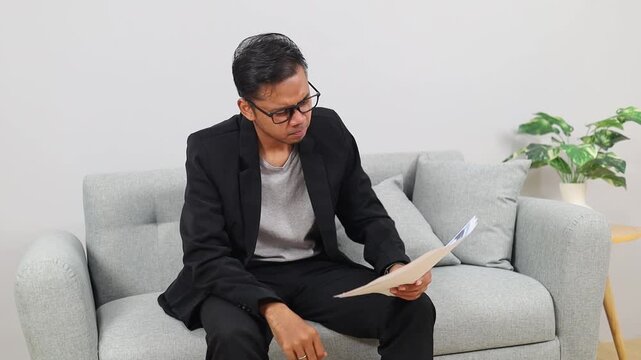 Stressed Asian businessman annoyed with low sales, see critical mistake incorrect information in paper document