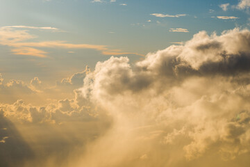 Fototapeta premium Thick cumulus cloud edge blocking the setting sun and creating distinct golden light rays shining down through the evening sky.