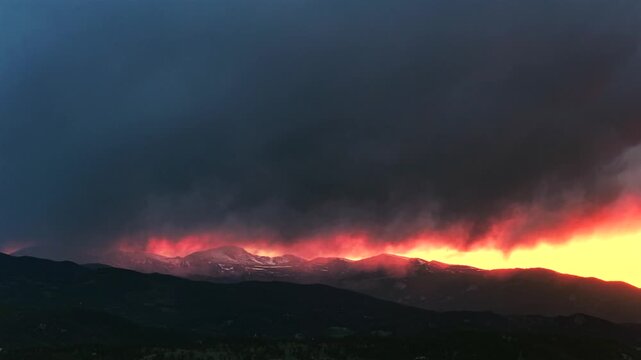 Sunset golden hour vibrant orange fire skies dark thunderstorm rain cloud Spring snow covered Mount Blue Sky aerial drone Colorado Rocky Mountains Mount Evans Wilderness front range peaks stormy pan