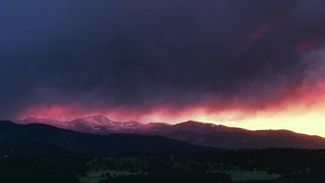 Sunset golden hour vibrant orange dark thunderstorm rain cloud fire orange sky Mount Blue Sky aerial drone Evergreen Colorado Rocky Mountains forward Springtime Mount Evans Wilderness Front Range