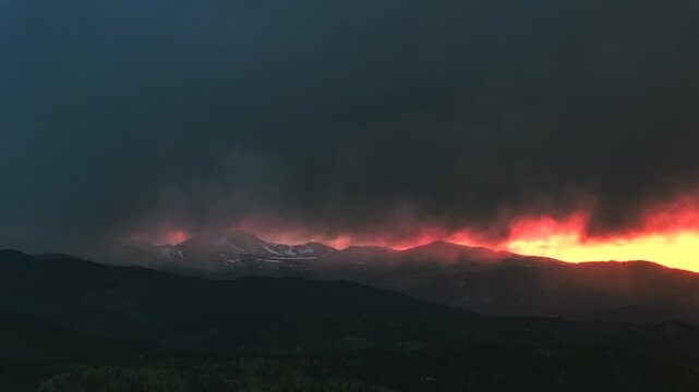 Sunset golden hour vibrant orange dark thunderstorm rain cloud fire orange sky Mount Blue Sky aerial drone Colorado Rocky Mountains Spring snow covered Mount Evans Wilderness front range peaks pan