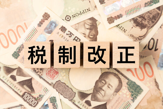 「税制改正」と書かれたブロックとたくさんの一万円札