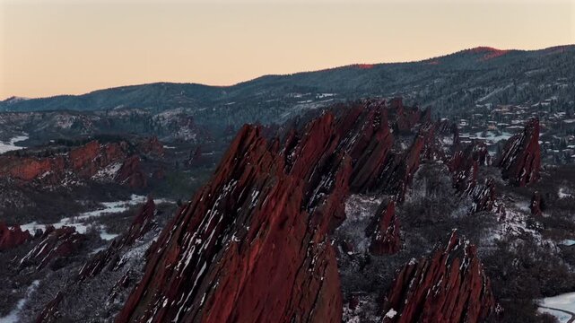Springtime sunset snow-covered jagged Red Rocks Peaks Fountain Valley Trail Arrowhead Golf Course Roxborough State Park Sterling Ranch Colorado aerial drone golden hour Denver Front Range circle right