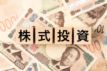 Fototapeta premium 「株式投資」と書かれたブロックとたくさんの一万円札