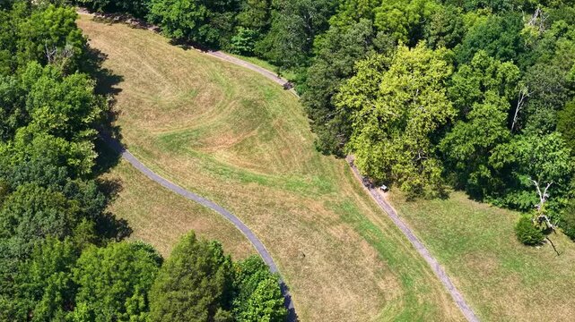 Aerial view of a serpentine mound in an open field, flanked by trees and intersected by paths.