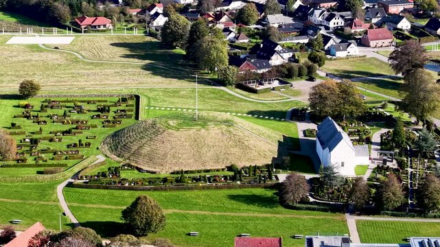 Aerial drone view of Jelling Viking burial mound beside historic church within UNESCO heritage landscape in Denmark