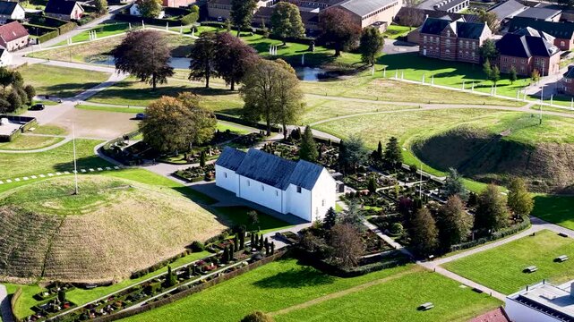 Aerial drone view of Jelling Church surrounded by Viking burial mounds and historic Danish landscape