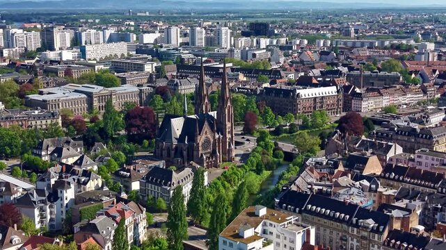 Saint Paul Church in Strasbourg, Bas-Rhin, Grand Est, France, featuring Neo-Gothic twin spires beside canal corridors and historic European urban architecture, oblique forward flyover shot.