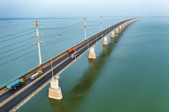 Aerial view of Jamuna Bridge with trucks and a bus crossing the wide river Tangail District, Dhaka Division, Bangladesh.