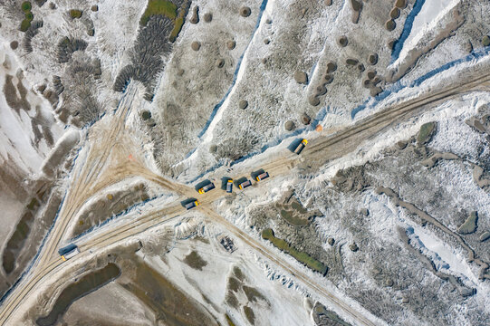 Aerial view of trucks driving on a dirt road across the textured sandy landscape of the Jamuna River Char in Tangail District, Dhaka Division, Bangladesh.
