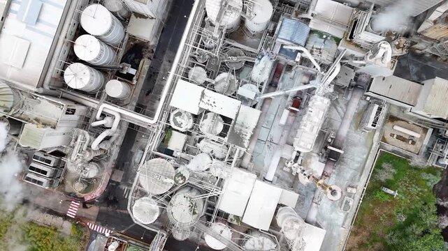 Aerial view of the Ence Biofactory industrial complex with white silos, pipes, and steam rising from chimneys in Pontevedra, Pontevedra, Spain.