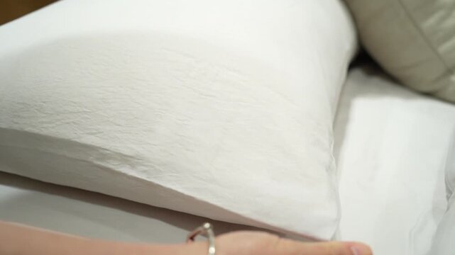 A close-up view of a woman's hand  checking a pillow's softness while browsing through household products in a shopping mall.