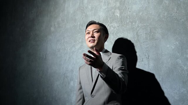 グレー背景で笑顔でプレゼンをする日本人男性