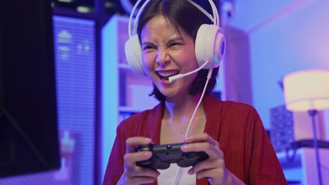 Excited young Asian girl playing video game with headset and joy stick controller at home.