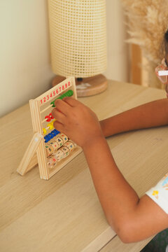 Child explores numbers using a wooden abacus tool