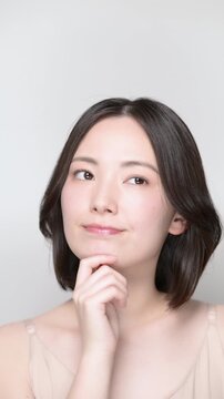 美容やセルフケアをどうしようか迷う、考え事をする若い女性の縦動画
