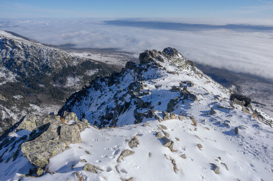View of the snow-covered rocky peak of Slavkovsky nos overlooking a thick sea of clouds in the High Tatras mountains Vysoke Tatry, Presov Region, Slovakia.