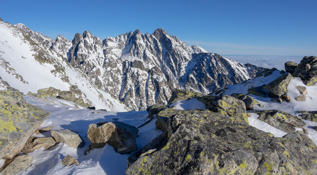 View of the snow-covered peaks of Slavkovsky nos and the High Tatras mountains under a clear blue sky from a rocky ridge Vysoke Tatry, Presov Region, Slovakia.