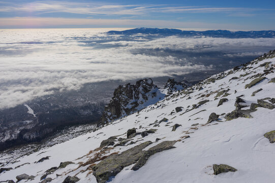 View of the snowy slopes of Slavkovsky nos overlooking a sea of clouds in the valley under a clear blue sky in Vysoke Tatry, Presov Region, Slovakia.