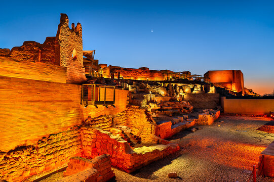 The historic mud brick ruins of At Turaif in Diriyah, Saudi Arabia, illuminated at dusk under a blue twilight sky.