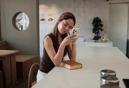 Young woman feeling tired using smartphone at coffee shop