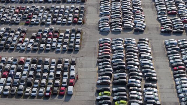 Aerial drone view of electric and gasoline cars awaiting customs clearance in a large vehicle storage lot, automotive industry, car production, import or export industry concept. 