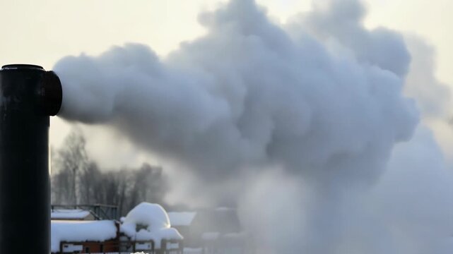 Smoke billows from black chimney pipe against snowy landscape, showcasing gradual increase in steam volume and density in industrial setting during winter