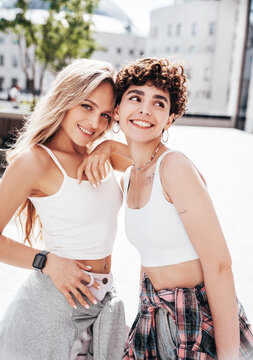 Two young beautiful smiling hipster female in trendy summer white t-shirt and shorts clothes. Sexy carefree women posing in the street. Positive models having fun, hugging and going crazy