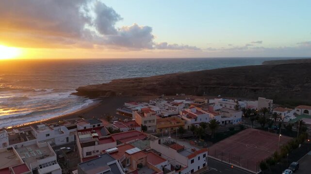 Scenic aerial capture of sunset casting amber hue on choppy ocean waves and rocky formations