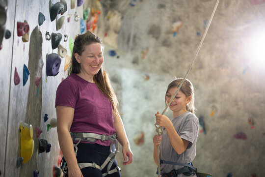 Kid climbs wall with support from adults while having fun and learning new skills at a climbing gym in the afternoon