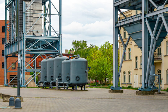 Architectural detail of the revitalized EC1 complex in Lodz, showing a geometric facade made of gray panels, regular rows of rectangular windows and a diagonal metal pipe.