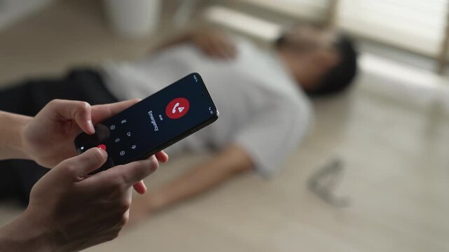 Woman calling emergency service to aid unconscious man lying on the floor