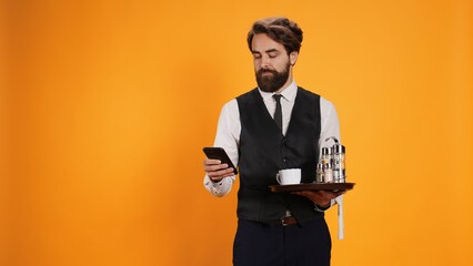 While carrying restaurant plate with utensils and posing for pictures, food service worker is...
