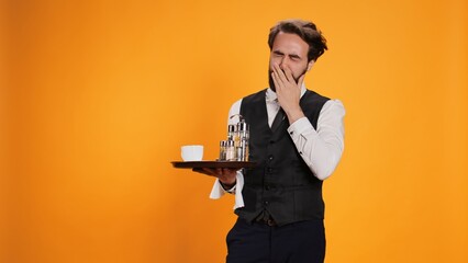 Exhausted butler feeling sleepy on camera, yawning and falling asleep on duty at restaurant. Waiter...