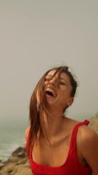 Woman passionately singing with spirited movements by rocky coast