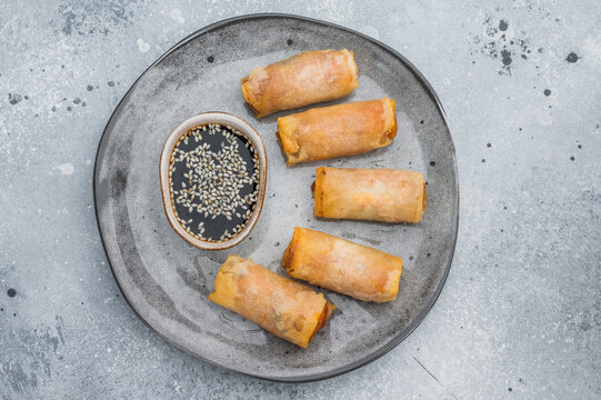 Crispy fried spring rolls served with soy dipping sauce and sesame seeds Asian appetizer flat lay on stone background