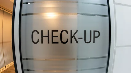Close-up of a check-up text sign on a frosted glass door in a modern, clean medical clinic or hospital interior. Healthcare, wellness, and medical examination concept. © CanYalicn
