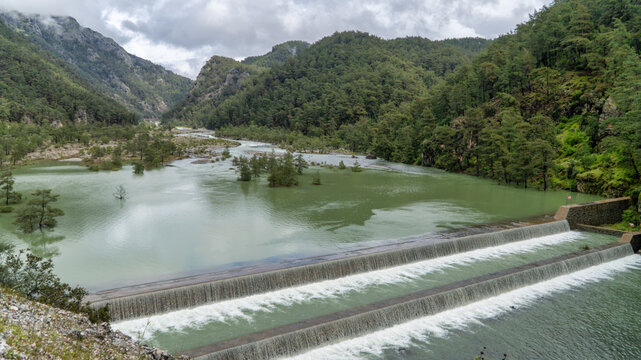 Namnam River cascade over a stepped weir between moss covered rocky cliffs and dense pine forest in Mugla, Turkey