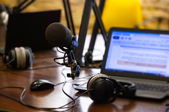Audio recording equipment and computer peripherals arranged on a wooden table, prepared for a broadcast or digital content creation session