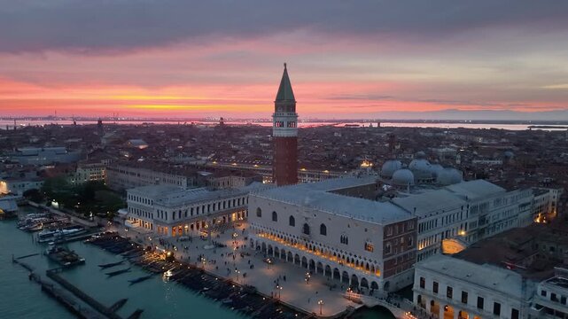 Venice aerial sunset over lagoon, boats gliding past basilica santa maria della salute, pastel sky casting. Italy
