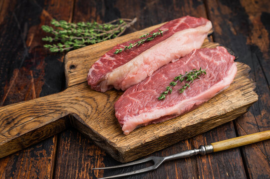 Uncooked picanha also called culotte or top sirloin cap, marbled beef steak with fat cap, rustic presentation on wooden board