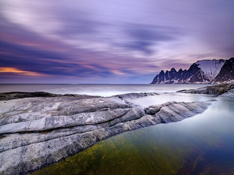 Natural pool on granite beach, Devils Teeth mountain peak in the back, Okshornan mountain range, Tungeneset, Senja Island, Troms, Norway