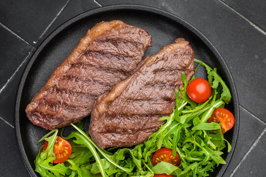 Juicy grilled beef culotte steak with arugula salad, sirloin cap cut served for healthy lunch or dinner
