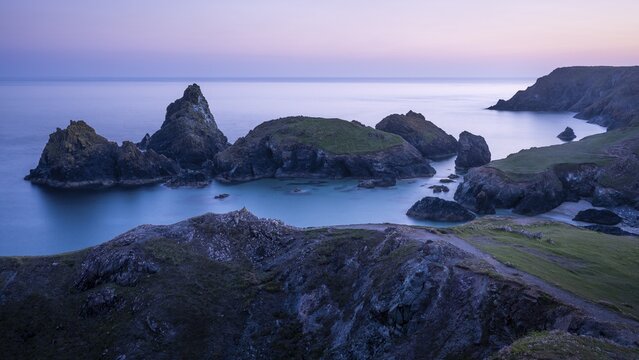 Kynance Cove with Asparagus Island, with sea, sandy beach and rocks in the evening. Coastal landscape. Blue hour. Long exposure. Good weather, blue sky. Kynance Cove, Lizard Peninsula, Cornwall, England, Great Britain